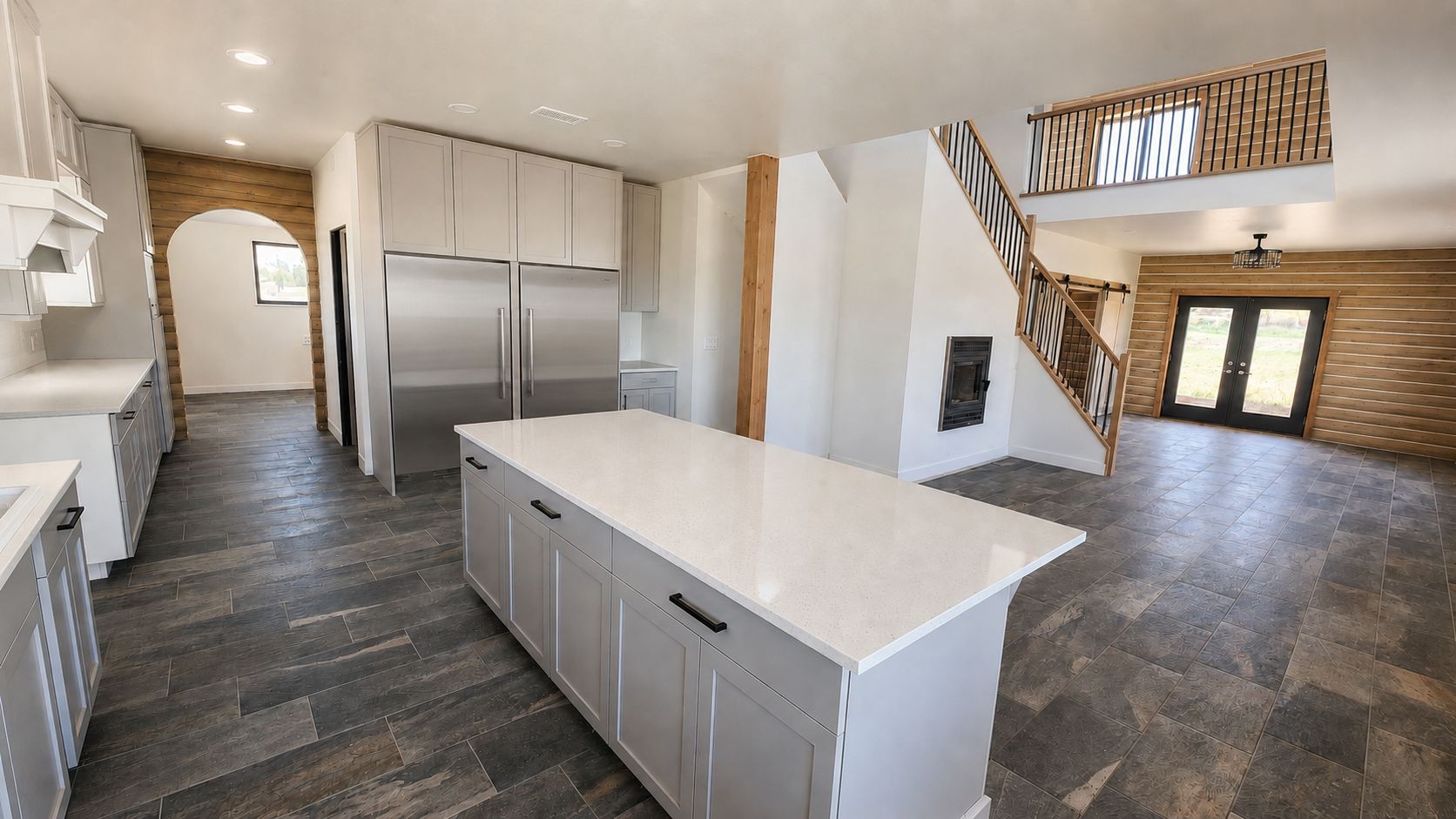 Finished custom kitchen with two stainless refrigerators, log walls, and black-and-wood stair and loft railings